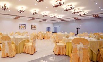 a large banquet hall with multiple dining tables covered in gold tablecloths and chairs arranged for a formal event at Graces Resort