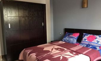 a bedroom with a wooden closet and bed , featuring a red and pink patterned comforter at Sunset View Apartments