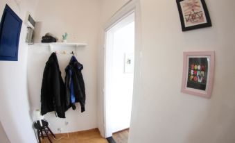 a white hallway with a coat rack and a doorway leading to another room , both adorned with coats at Downtown Apartments