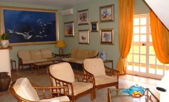 a living room with wooden furniture , including chairs and a couch , surrounded by paintings on the wall at Hotel Royal