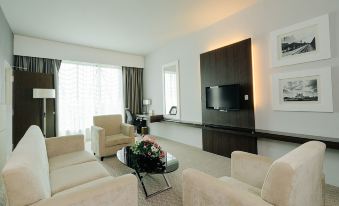 a modern living room with a large flat - screen tv mounted on the wall , surrounded by comfortable couches and chairs at Raia Hotel & Convention Centre Alor Setar