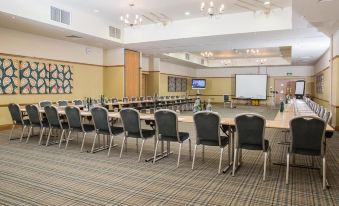 a conference room with rows of chairs arranged in a semicircle , and a projector screen mounted on the wall at Lancaster House Hotel