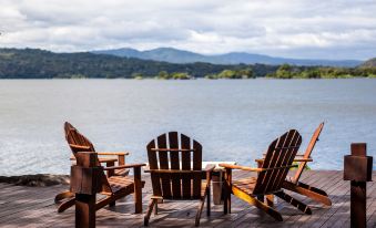 a wooden deck overlooking a lake , with several chairs placed on the deck for relaxation at Jicaro Island Lodge Member of the Cayuga Collection