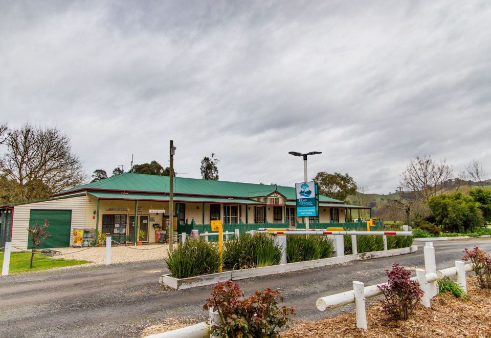 a motel with a green roof , surrounded by trees and a parking lot , under a cloudy sky at Big4 Breeze Holiday Parks - Eildon