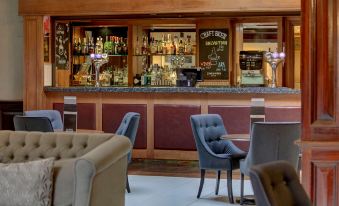 a bar with a variety of bottles and glasses , as well as chairs and couches at Quorn Country Hotel