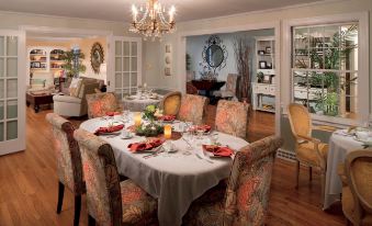 a dining room with a large round table set for a formal dinner , surrounded by chairs and adorned with red napkins at The Homestead