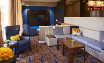 a hotel lobby with various seating options , including couches , chairs , and a coffee table , as well as a television at Courtyard Chicago Deerfield