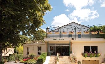 a hotel building with a large sign above the entrance , surrounded by trees and bushes at Mercure Castres l'Occitan