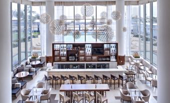 a modern restaurant with white walls , large windows , and an elegant dining area with multiple tables and chairs at Guyana Marriott Hotel Georgetown