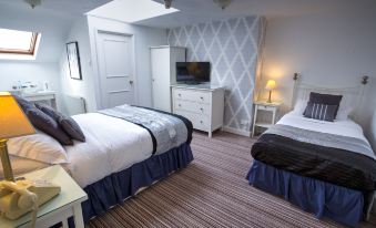 a room with two beds , one on each side of the room , and a television in the corner at The Ascott