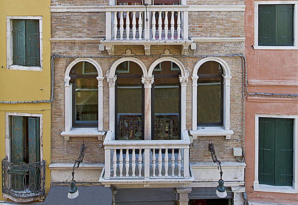 a building with balconies and white windows , possibly a bakery or cafe , located in a european town at Hotel Nazionale