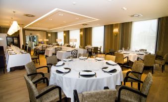 a large dining room with round tables covered in white tablecloths and chairs arranged around them at Hotel Bahía