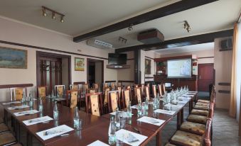 a large conference room with multiple long tables , wooden chairs , and water bottles arranged neatly for a meeting or event at Hotel Victoria