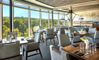 a dining room with a large table surrounded by chairs , and a view of trees outside the window at The Fontaine