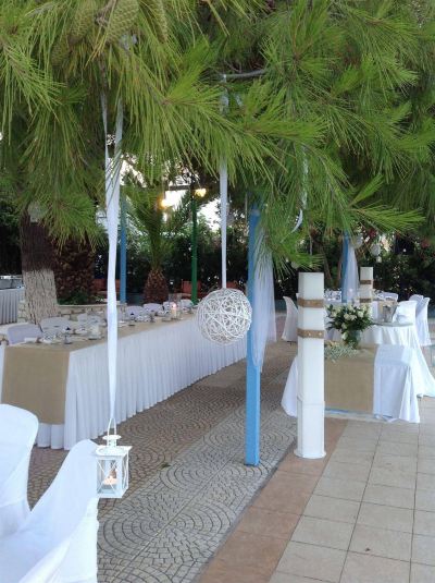 a well - decorated outdoor area with white tablecloths and blue trim , surrounded by palm trees and lush greenery at Hotel Summery