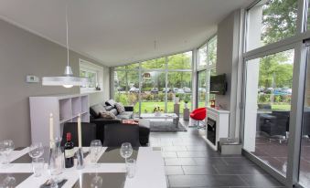 a modern living room with large windows , a dining area , and a kitchen , all decorated in neutral colors at EuroParcs de Rijp