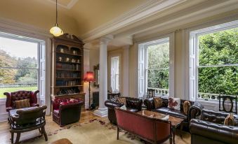a large living room with high ceilings , hardwood floors , and a large bookshelf filled with books at Doxford Hall Hotel and Spa
