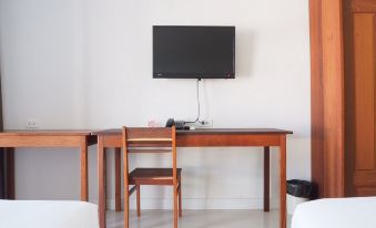 a wooden desk with a tv mounted on the wall above it and two beds nearby at Klongyai Center