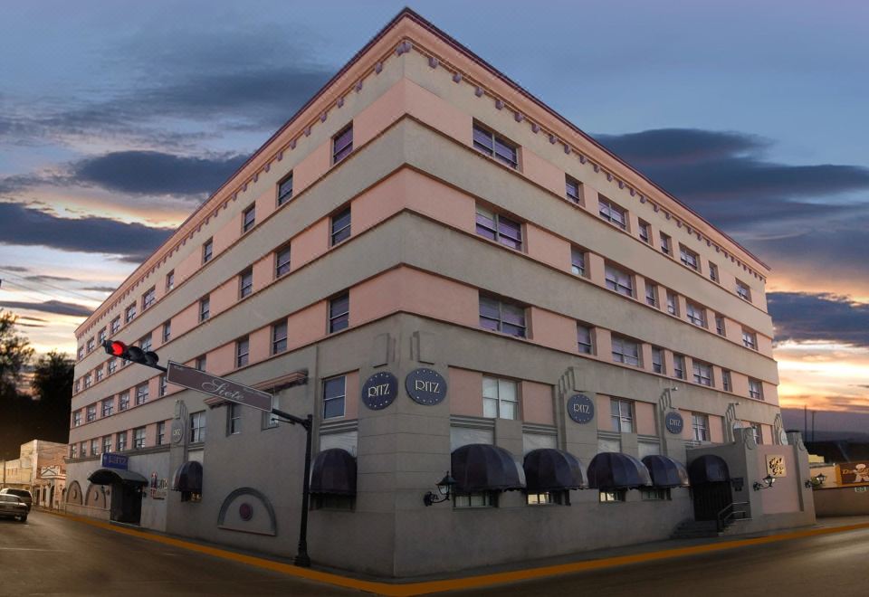 a large building with a few cars parked in front and a traffic light in the middle at Hotel Ritz