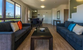 a modern living room with black couches , a dining table , and a view of the ocean at Rosslyn Bay Resort