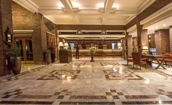 a large hotel lobby with marble floors , a reception desk , and several chairs arranged in a symmetrical fashion at Faisalabad Serena Hotel