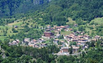 a picturesque village nestled in a lush green valley , surrounded by mountains and trees , with a small town visible in the background at Miravalle