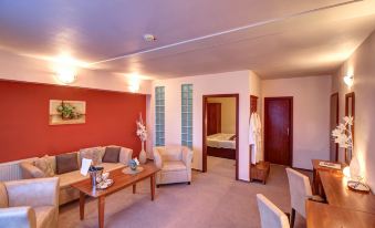 a living room with a couch , coffee table , and chairs is shown next to a bedroom at Hotel Dixon