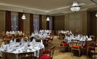 a large dining room with multiple tables covered in white tablecloths and chairs arranged for a formal event at Grand Hôtel la Cloche Dijon - MGallery