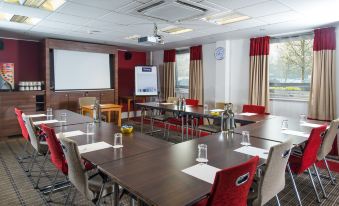 a conference room set up for a meeting , with tables and chairs arranged in a semicircle at Holiday Inn Express Milton Keynes