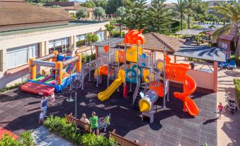 an aerial view of a large playground with colorful play equipment , surrounded by trees and buildings at Zafiro Can Picafort
