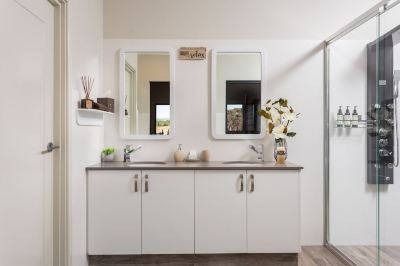 a modern bathroom with white walls , wooden floor , and two large mirrors above the vanity at The Swan Valley Retreat