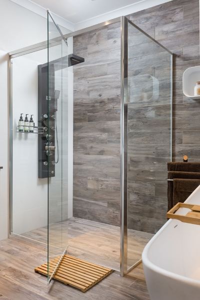 a modern bathroom with a glass shower enclosure , wooden walls , and a black bathtub filled with water at The Swan Valley Retreat