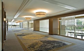 a long , empty hallway with a carpeted floor and multiple chandeliers hanging from the ceiling at Sheraton Valley Forge King of Prussia