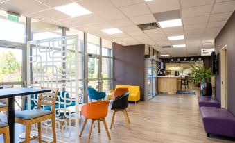 a brightly lit room with various chairs and couches arranged in a seating area , creating a comfortable environment for work or leisure at Comfort Hotel Aeroport Lyon St Exupery