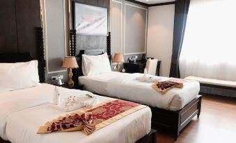 A bedroom with two beds and a red bedspread is located on the left side at Aaron Vientiane Hotel