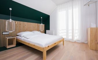 a bed with white sheets and a wooden headboard is in a room with a window at Colors Apartments