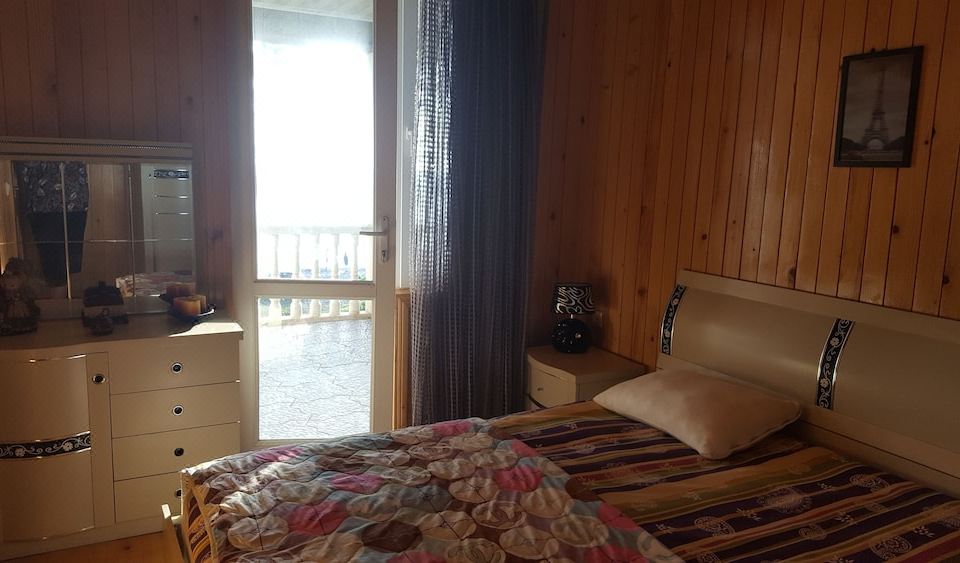 a bedroom with a wooden wall , bed , and window , looking out onto a balcony with a view at Villa Eli