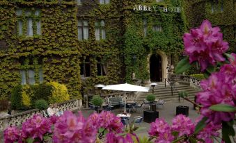 a large hotel with a courtyard filled with lush greenery and purple flowers , creating a peaceful and serene atmosphere at The Abbey