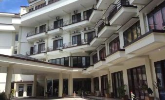 a modern hotel building with multiple floors and balconies , featuring an outdoor seating area and greenery at Hotel Grand Papua Fakfak