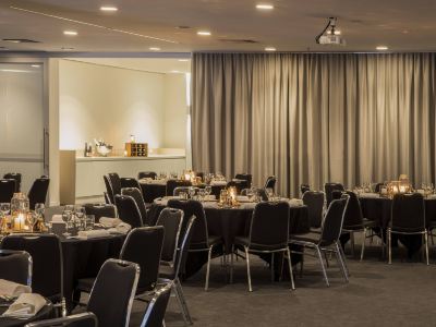 a large conference room filled with tables and chairs , ready for a meeting or event at Ibis Melbourne Hotel and Apartments