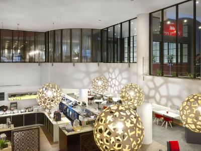 a modern office space with multiple desks , chairs , and a bar area , as well as large round gold ornaments on the floor at Ibis Melbourne Hotel and Apartments