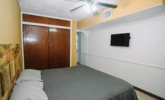 a clean and well - organized bedroom with a bed , a closet , and a tv mounted on the wall at La Esperanza