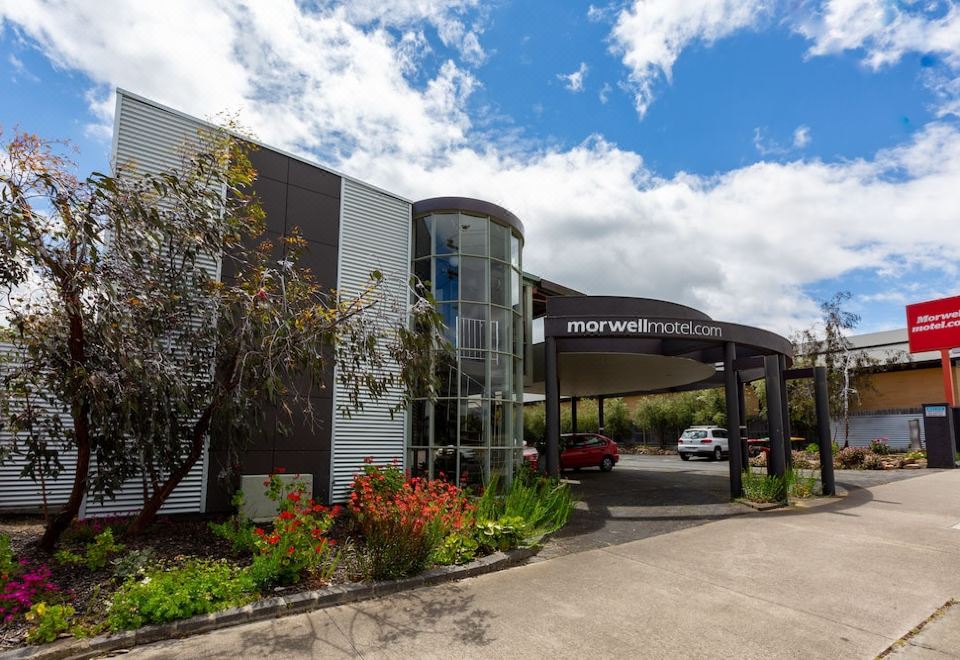 a modern building with a curved glass entrance and a car parked in front of it at Morwell Motel