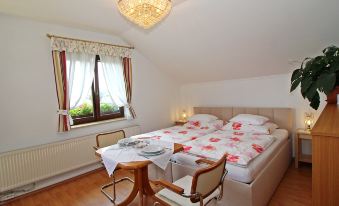 a cozy bedroom with a bed , nightstands , and a dining table , decorated with white bedding and curtains at Anita