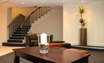 a modern living room with a wooden table , chairs , and a staircase in the background at Lansdowne Hotel