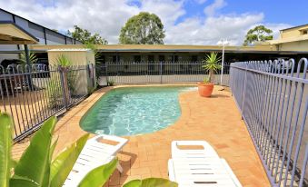 a small backyard with a swimming pool surrounded by chairs and a fence , creating a relaxing atmosphere at Boulevard Lodge Bundaberg