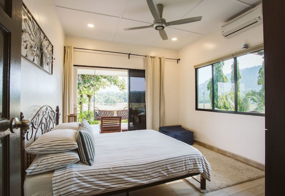 a spacious bedroom with a large bed , white walls , and a sliding glass door leading to a balcony at Kampung Bongsu Farmstay