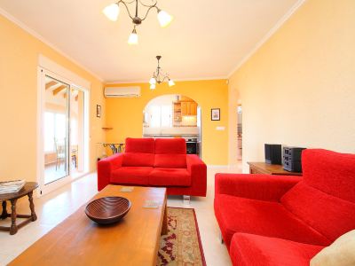 a cozy living room with a red couch , a television , and a dining table in the background at Joli Joli Photo