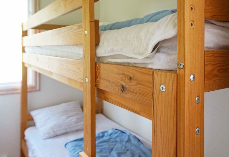 a wooden bunk bed with a white mattress and blue blanket on the top bunk at Simrishamn