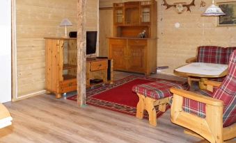 a cozy living room with wooden furniture , including a couch , chairs , and a dining table at Helgeland